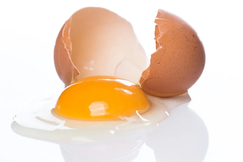 Image showing Cracking the Market: service. Cracked egg with the york on a flat white surface